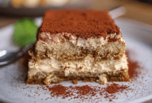 Delicious tiramisu dessert with creamy layers and a dusting of cocoa powder on a white plate