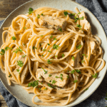 Louisiana-style chicken pasta on a rustic plate, featuring a creamy Cajun sauce, tender chicken, and perfectly cooked linguine, garnished with fresh herbs.