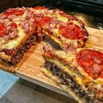 Homemade pizza burger pie with a crispy golden crust, gooey melted cheese, seasoned ground beef, and colorful pizza toppings, perfect for a hearty and flavorful meal