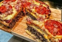 Homemade pizza burger pie with a crispy golden crust, gooey melted cheese, seasoned ground beef, and colorful pizza toppings, perfect for a hearty and flavorful meal