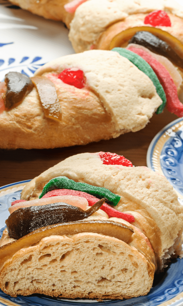 Detailed view of Rosca de Reyes sections, showcasing its soft bread texture and vibrant candied fruits on top.